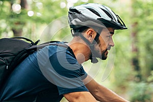 Side view closeup portrait of cyclist man riding bike in the mountain. Athlete male in cycling gear bicycling outdoor on nature