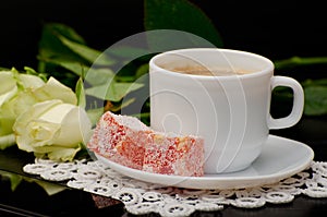 Side view of a coffee cup with milk close-up, oriental sweets. smartphone, white roses on a black background