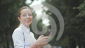 Side view of a college girl text messaging mobile phone in the park. closeup