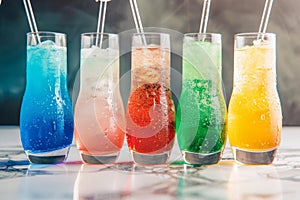 Side view of colorful iced drinks in various flavors, casting playful reflections