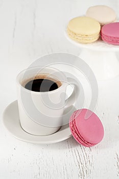 Side view colorful macaroons and cup of coffee on wooden table