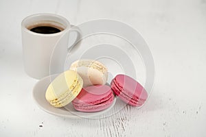 Side view colorful macaroons and cup of coffee on wooden table