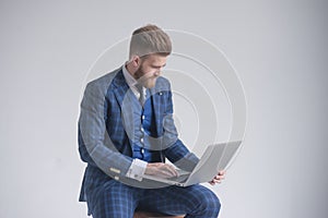 Side view of concentrated businessman in armchair working on laptop