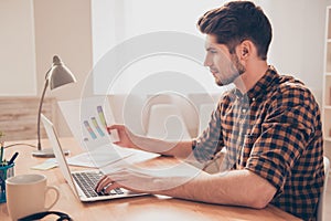 Side view of concentrated young man working with laptop and diagrama