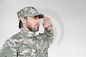 side view of confident bearded soldier in military uniform saluting