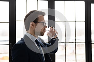 Side view confident businessman wearing glasses drinking pure mineral water