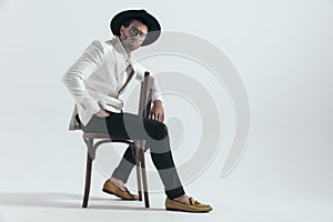 side view of confident elegant man with arms over chair sitting