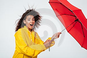 Side view of confused surprised african woman in raincoat