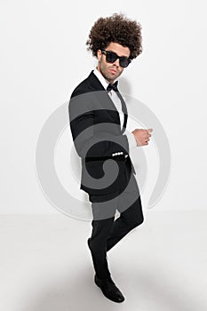 side view of cool fashion man with big hair walking and looking forward