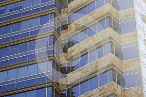 Side view of a corporate building faÃ§ade made of glass windows and cream yellowish tiles.