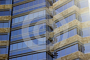 Side view of a corporate building faÃ§ade made of glass windows and cream yellowish tiles.