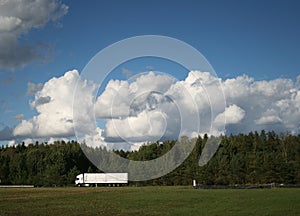 Side view on country road and heavy white truck with forest