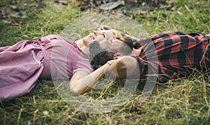 Side view couple lying on grass and looking at sky. Young people relaxing in park or forest. Summer holiday romance