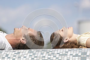 Side view of couple relaxing on mosaic wall