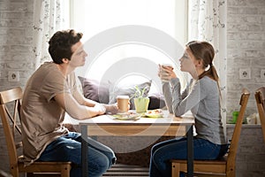 Side view couple sitting in cafe drinking coffee eating pizza