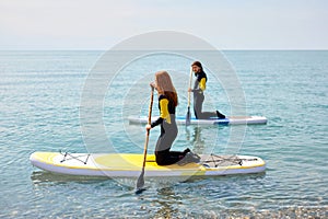 Side view on couple stand up paddleboarding at sea. Young couple doing watersport