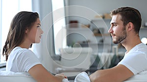 Side view of a couple talking sitting on a couch and looking each other at home.