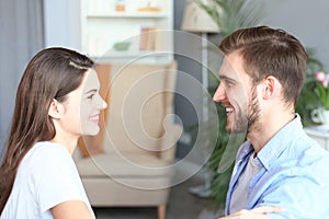 Side view of a couple talking sitting on a couch and looking each other at home.