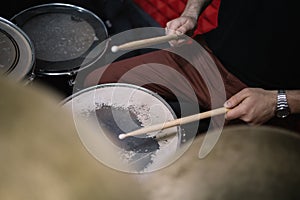 Side view of cropped drummer playing drums with sticks