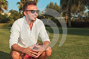 Side view of a crouched smiling man wearing sunglasses