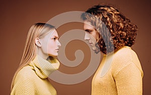 Side view. Curly man and blonde woman facing each other, eyes open. Concept of confrontation in the family. A couple