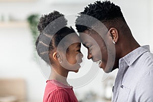 Side view of cute black father and daughter touching foreheads