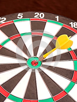 Side view of a dartboard with a dart in the bull`s eye.