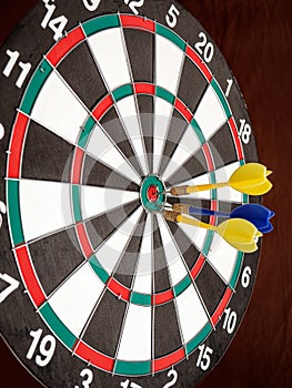 Side view of a dartboard with three darts in the bull`s eye.