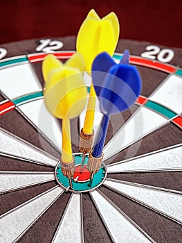 Side view of a dartboard with three darts in the bull`s eye. Well-aimed dart throwing.