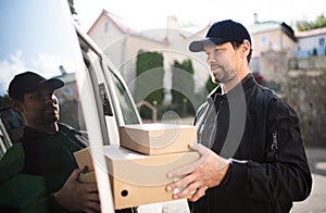 Side view of delivery man courier delivering parcel box in town.