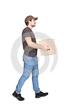 Side view delivery man on the move, full length portrait, walking and carrying a cardboard parcel box to customer, isolated on