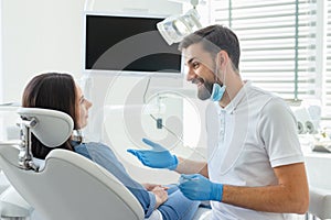 Side view of dentist advicing and gesturing to patient in modern clinic photo