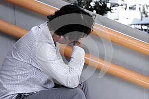 Side view of depressed stressed young Asian business man with hands touching head and feeling disappointed or exhausted with job.