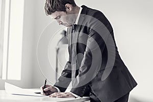 Side view of a designer or draftsman using ruler and pencil while working at the plan