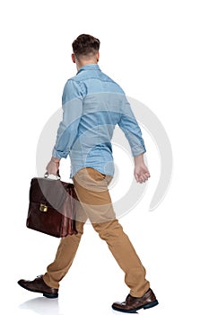 Side view of a determined casual man holding briefcase