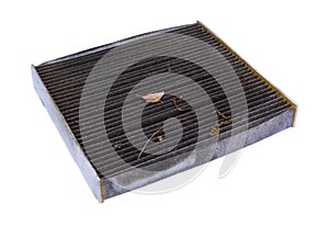 Side view of a dirty cabin air filter at an angle with dried leaves and dirt isolated on a white background