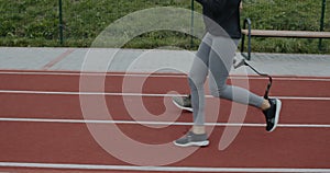 Side view of disabled man and sports woman taking position on marks and start running. Male athlete with running blade