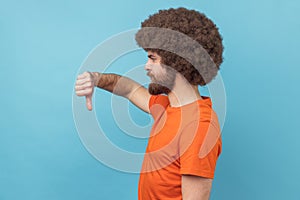 Side view of displeased man showing thumbs down dislike gesture, symbol of disagree.