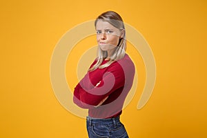 Side view of dissatisfied young blonde woman in casual clothes posing isolated on yellow orange background in studio