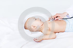 Side view of doctor examining cute little baby boy with stethoscope isolated on white