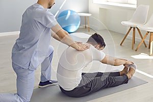 Side view doctor helps the patient to do stretching exercises and yoga after the injury.