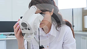 Side view of a doctor in a white suit examining a woman with a colposcopy in a gynecological clinic