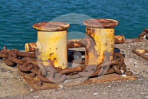 Side View of A double bitt mooring bollard with a heavy chain around it.