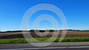 Side View Driving by Rural Farmland in Day.  Driver Point of View POV Driving Past Countryside Farm