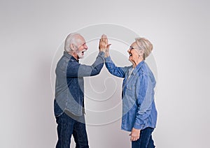 Side view of ecstatic senior couple giving high-five to each other and screaming on white background