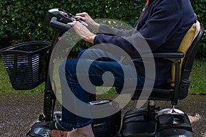 Side view of elderly lady riding a mobility scooter.