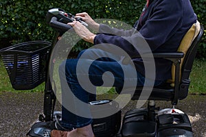 Side view of elderly lady riding a mobility scooter. photo