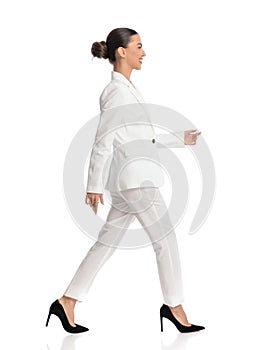 side view of elegant businesswoman with bun smiling and walking