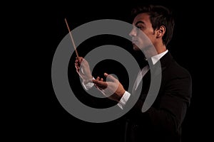 Side view of an elegant music conductor holding a batton photo