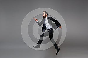 Side view of excited young business man in classic suit shirt tie posing  on grey background. Achievement career